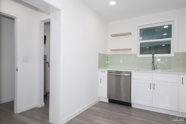 kitchen with white cabinetry, sink, backsplash, stainless steel dishwasher, and light hardwood / wood-style floors