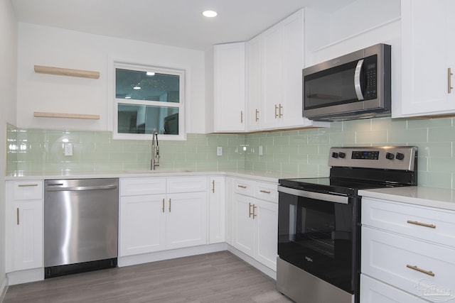 kitchen featuring sink, white cabinetry, stainless steel appliances, light hardwood / wood-style floors, and decorative backsplash