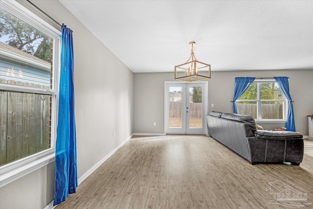 living room with a notable chandelier, light hardwood / wood-style floors, and french doors