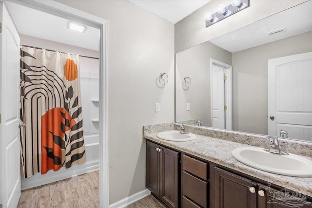 bathroom with hardwood / wood-style flooring, vanity, and shower / tub combo with curtain