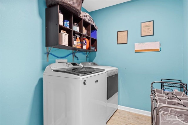 laundry room featuring washer and clothes dryer and light hardwood / wood-style flooring