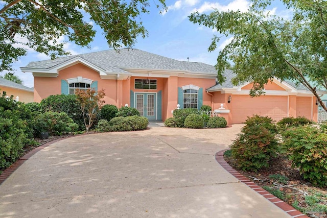 view of front facade featuring a garage, french doors, concrete driveway, and stucco siding