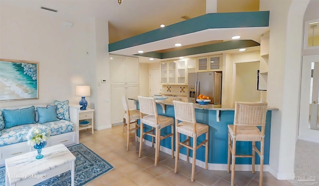 1129 Seabreeze Ln, Gulf Breeze, FL 32563 - kitchen with a kitchen breakfast bar, stainless steel fridge, light stone counters, a peninsula, and glass insert cabinets