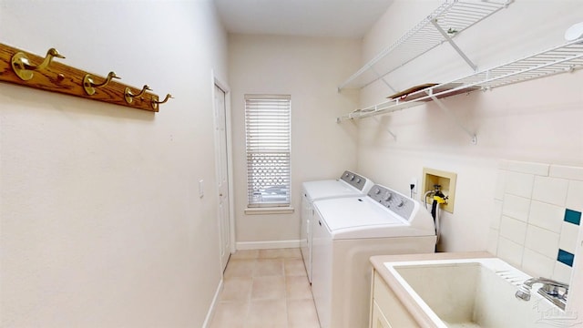 1129 Seabreeze Ln, Gulf Breeze, FL 32563 - clothes washing area featuring light tile patterned floors, baseboards, a sink, washer and dryer, and laundry area