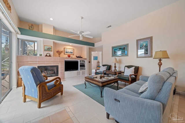 tiled living room with ceiling fan and a fireplace