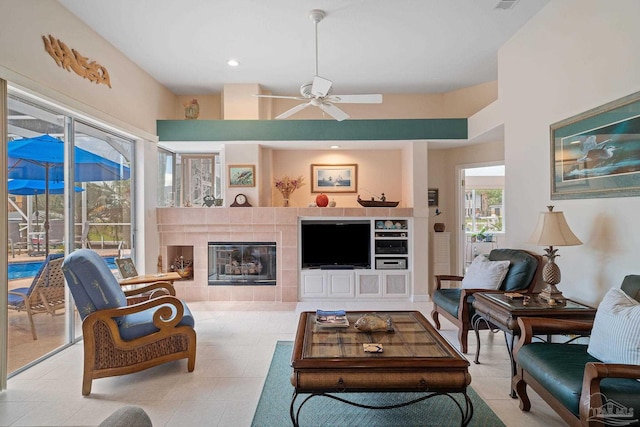 tiled living room with a tile fireplace and ceiling fan