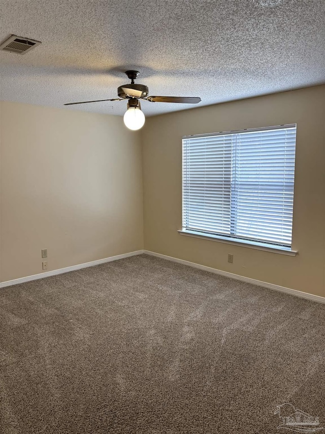 carpeted empty room with visible vents, baseboards, a textured ceiling, and ceiling fan