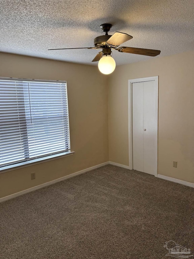 carpeted empty room featuring ceiling fan, baseboards, and a textured ceiling