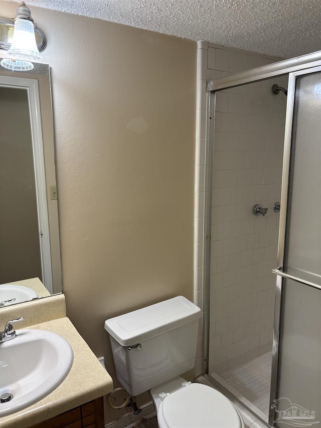 bathroom featuring vanity, a shower stall, toilet, and a textured ceiling