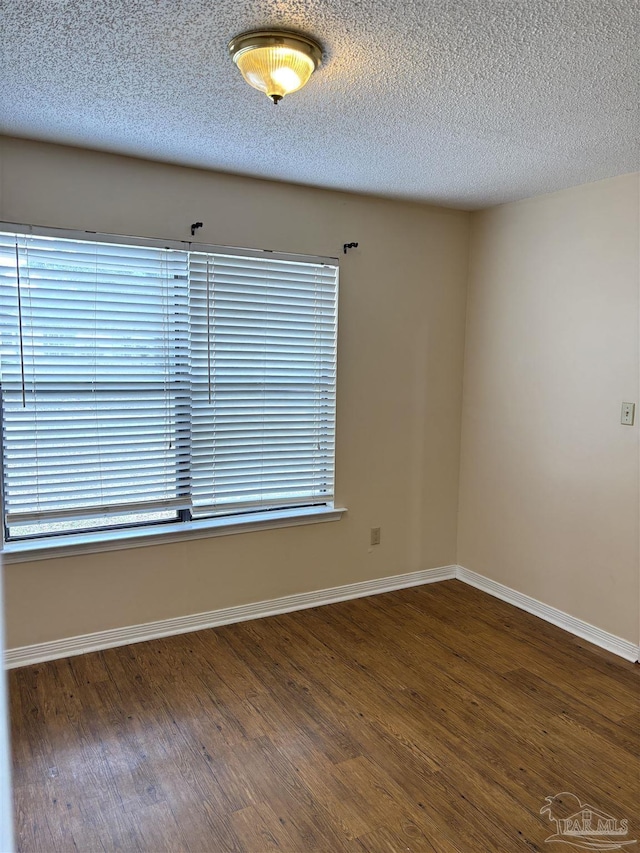 unfurnished room featuring baseboards, a textured ceiling, and wood finished floors