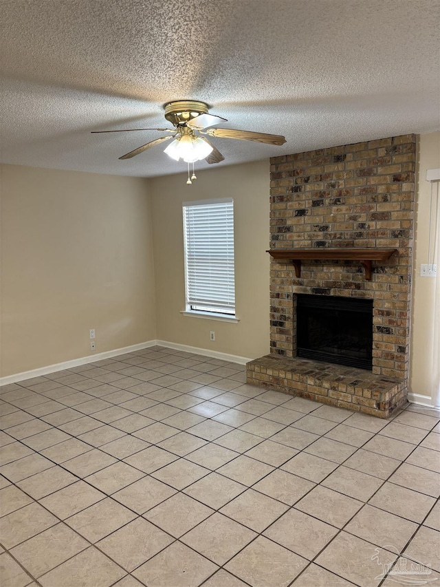 unfurnished living room with a textured ceiling, light tile patterned floors, baseboards, a brick fireplace, and ceiling fan