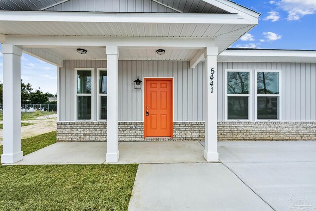 doorway to property with covered porch and a yard