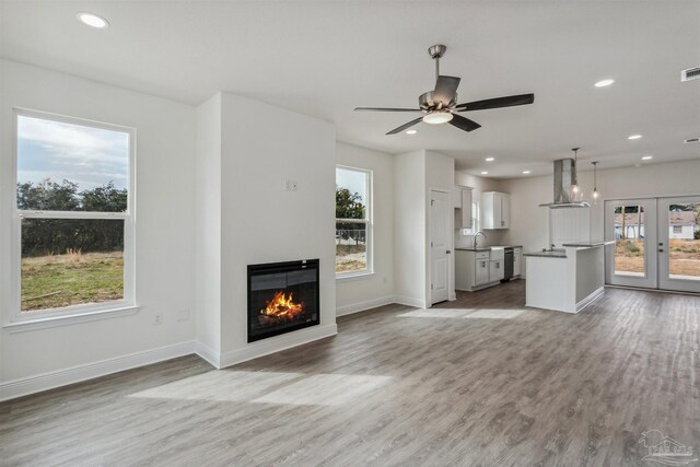 unfurnished living room featuring hardwood / wood-style flooring, plenty of natural light, and ceiling fan