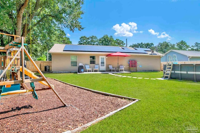 back of house featuring a lawn, a swimming pool, a patio area, and a playground