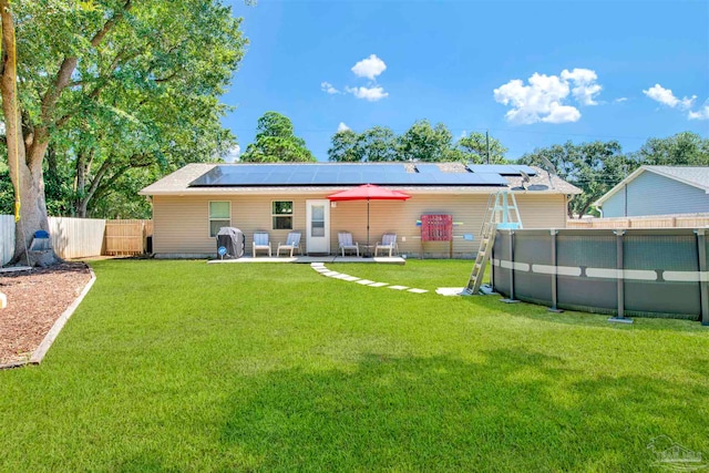 back of house with solar panels, a yard, and a patio