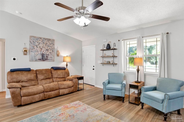 living room with vaulted ceiling, light hardwood / wood-style floors, ceiling fan, and a textured ceiling