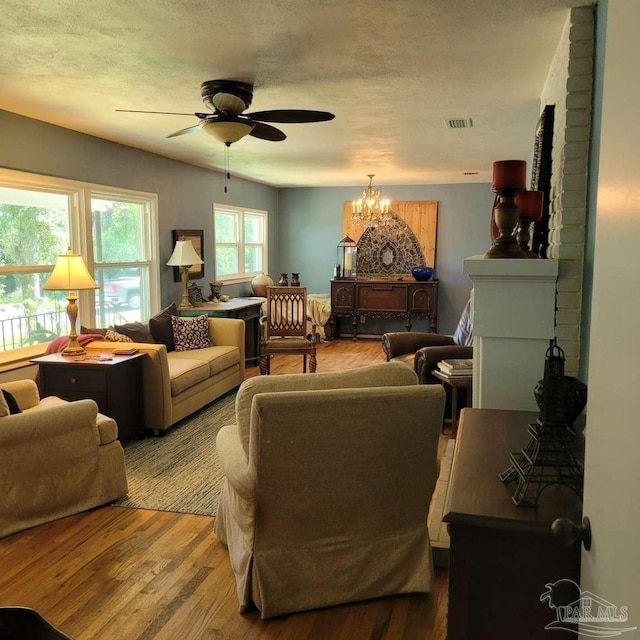 living room featuring a textured ceiling, ceiling fan with notable chandelier, and hardwood / wood-style flooring