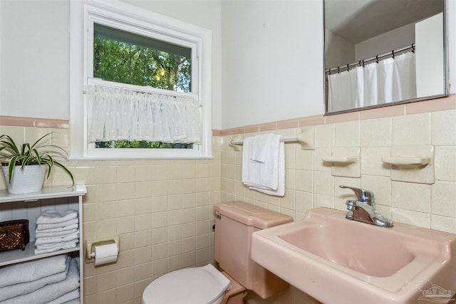 bathroom featuring tile walls, toilet, sink, and a shower with curtain