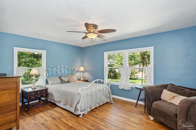 bedroom with multiple windows, ceiling fan, and hardwood / wood-style flooring