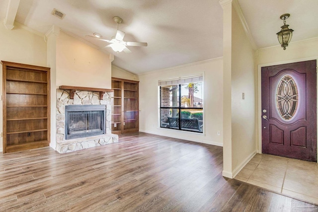 foyer featuring hardwood / wood-style floors, a fireplace, lofted ceiling, ceiling fan, and crown molding