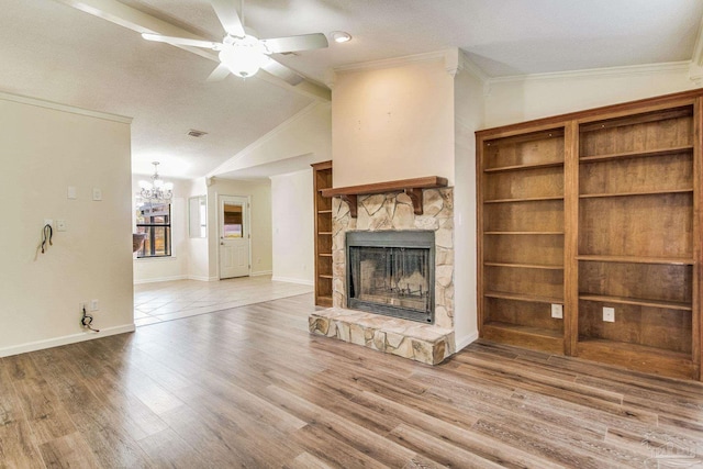 unfurnished living room featuring lofted ceiling, crown molding, ceiling fan with notable chandelier, hardwood / wood-style floors, and a stone fireplace