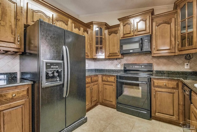 kitchen featuring light tile patterned flooring, crown molding, dark stone counters, decorative backsplash, and black appliances