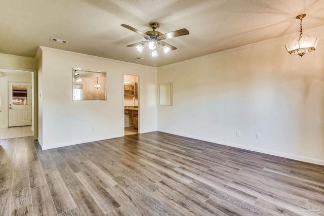 unfurnished living room with crown molding, ceiling fan, wood-type flooring, and a textured ceiling