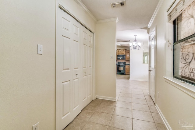 corridor featuring ornamental molding, light tile patterned floors, and an inviting chandelier