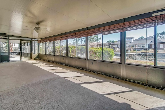 unfurnished sunroom featuring ceiling fan and a water view