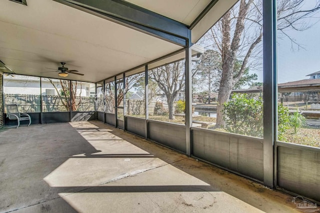 unfurnished sunroom featuring a water view, a wealth of natural light, and ceiling fan