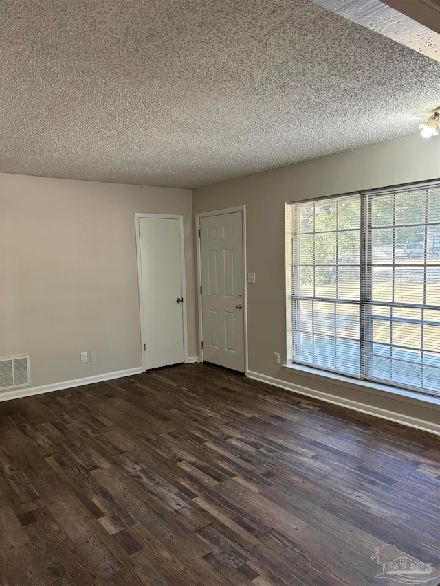 empty room featuring a textured ceiling and dark hardwood / wood-style flooring