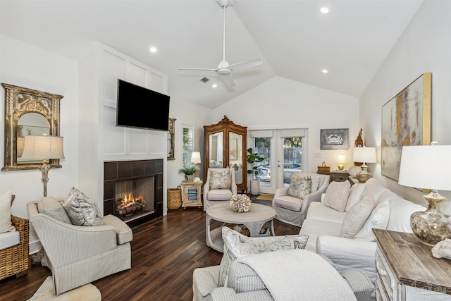 living room featuring french doors, dark wood-type flooring, a tile fireplace, high vaulted ceiling, and ceiling fan