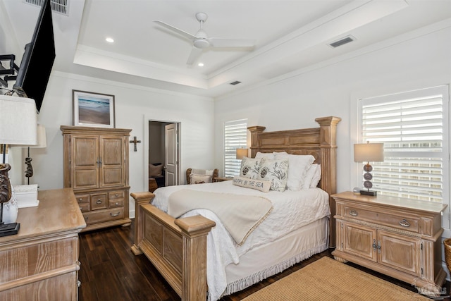 bedroom with dark wood-type flooring, multiple windows, a tray ceiling, and ceiling fan