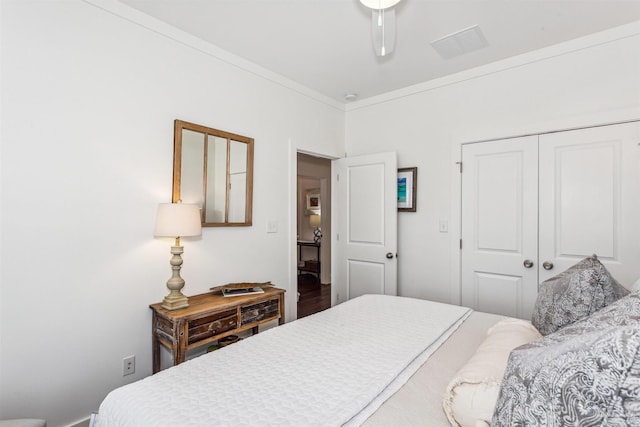 bedroom with a closet, wood-type flooring, crown molding, and ceiling fan