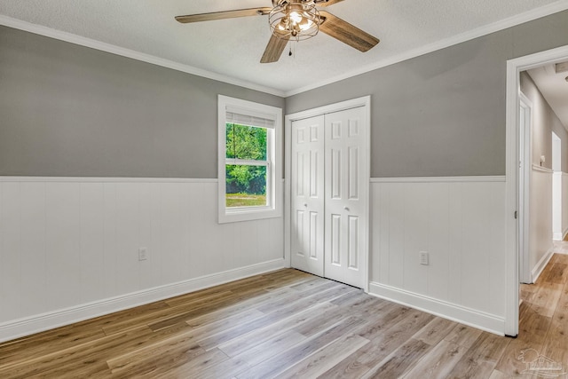 interior space featuring a closet, ceiling fan, crown molding, and light wood-type flooring