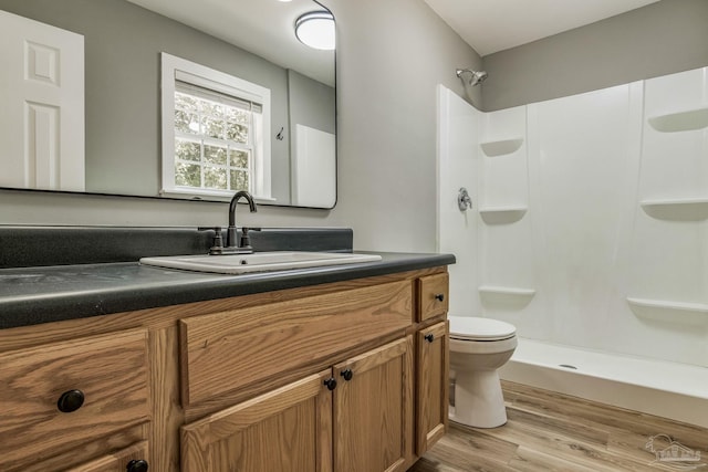 bathroom with toilet, hardwood / wood-style floors, a shower, and vanity