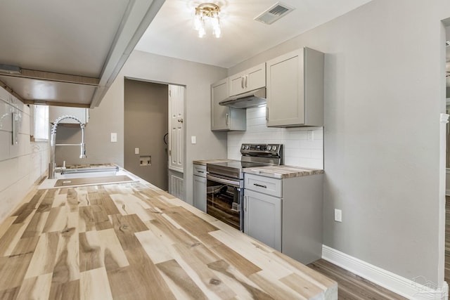 kitchen featuring butcher block counters, decorative backsplash, sink, wood-type flooring, and black range with electric cooktop