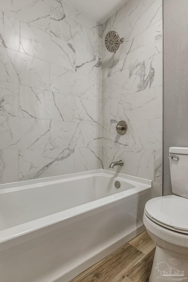 bathroom with tile patterned flooring, tiled shower / bath combo, and toilet