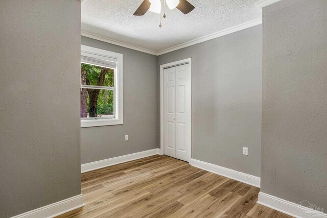 spare room featuring light wood-type flooring, ornamental molding, a textured ceiling, and ceiling fan