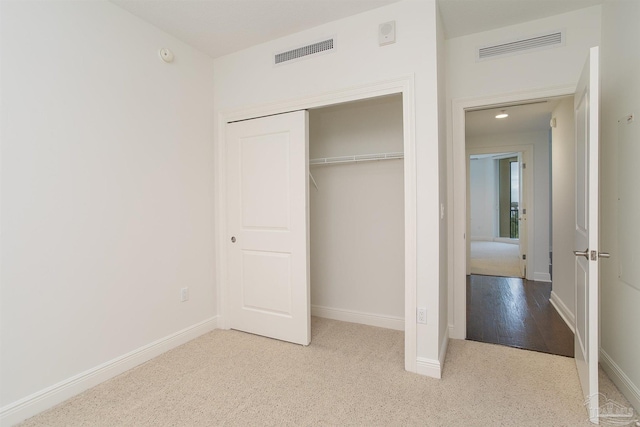 unfurnished bedroom featuring light carpet and a closet