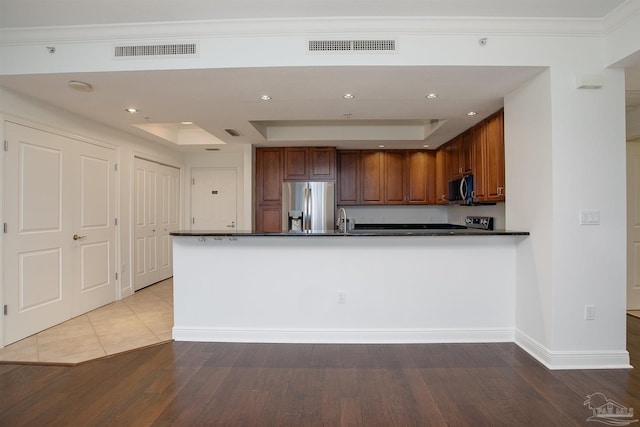 kitchen featuring sink, crown molding, a tray ceiling, stainless steel appliances, and hardwood / wood-style floors