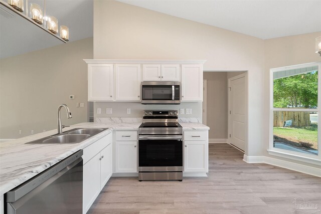 4485 Edgewood Dr, Milton, FL 32583 - kitchen with appliances with stainless steel finishes, a sink, vaulted ceiling, light wood-style floors, and white cabinetry