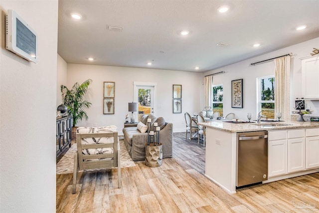 kitchen featuring light wood-type flooring, stainless steel dishwasher, white cabinetry, and plenty of natural light