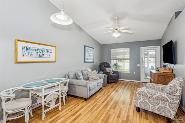 living room with light wood-style floors, baseboards, vaulted ceiling, and a ceiling fan