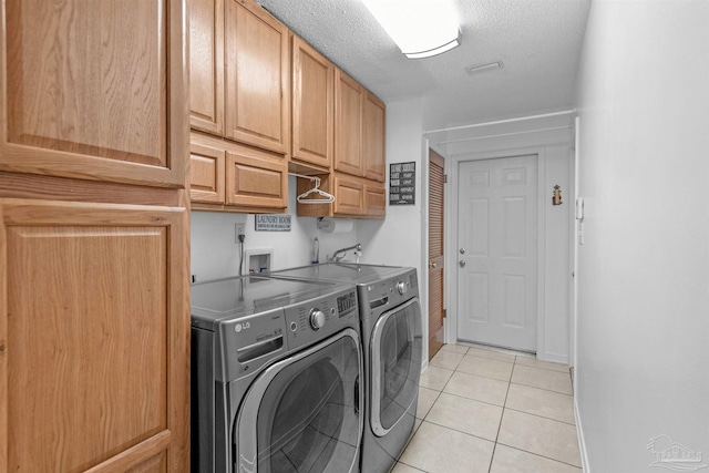 laundry room with cabinets, a textured ceiling, light tile patterned flooring, and washer and clothes dryer