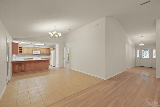 unfurnished living room featuring an inviting chandelier, lofted ceiling, a textured ceiling, and light hardwood / wood-style flooring