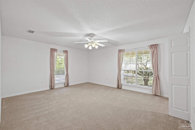 spare room featuring a textured ceiling, ceiling fan, a healthy amount of sunlight, and light carpet