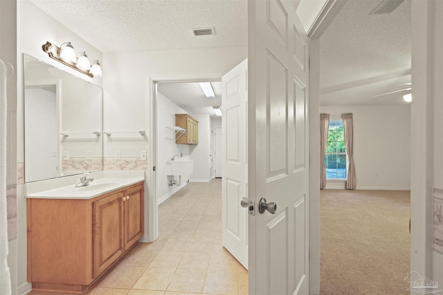 bathroom with tile patterned flooring, vanity, a textured ceiling, and ceiling fan