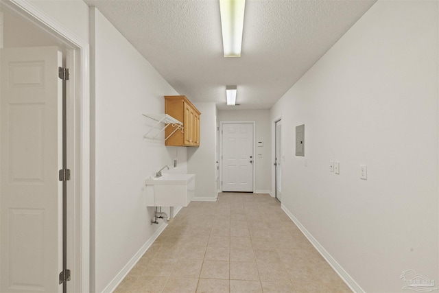 hallway with electric panel, sink, light tile patterned floors, and a textured ceiling