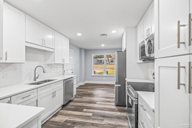 kitchen with stainless steel appliances, white cabinetry, dark wood-type flooring, and sink